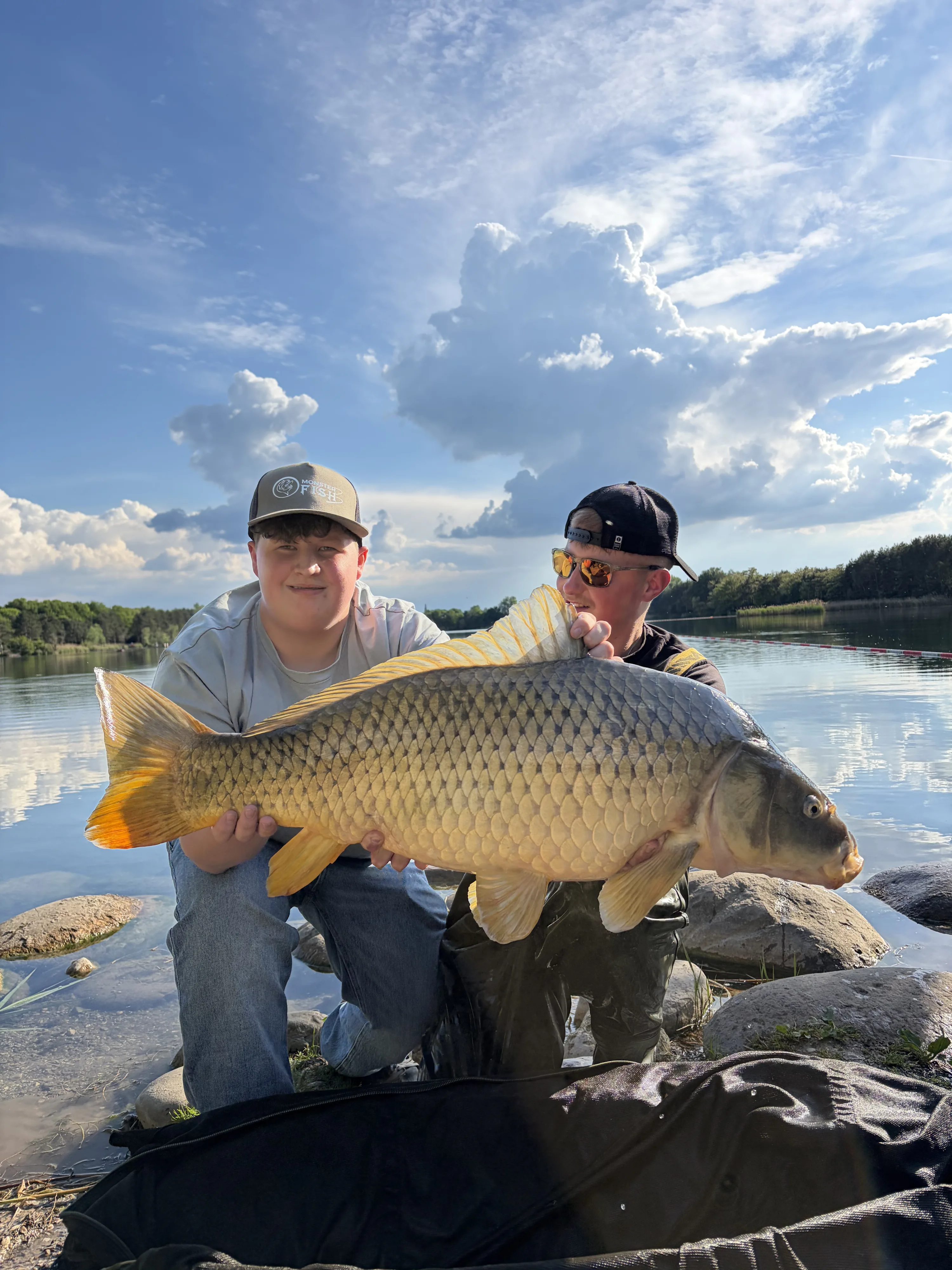 Zwei Angler mit Karpfen vor spiegelglattem See in der Abendstimmung